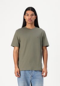 T-shirt in cotone verde oliva con colletto girocollo, maniche corte e un piccolo logo sul petto. Vestibilità casual e texture liscia.