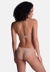 Soutien-gorge nude sans bretelles avec une bande arrière lisse et un bikini assorti, doté d'un tissu sans couture et de détails minimalistes pour un look épuré.