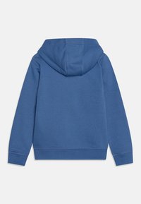 Sudadera azul con capucha ajustable, puños y dobladillo de canalé. Presenta una textura suave y un diseño minimalista, con costuras visibles en las uniones.