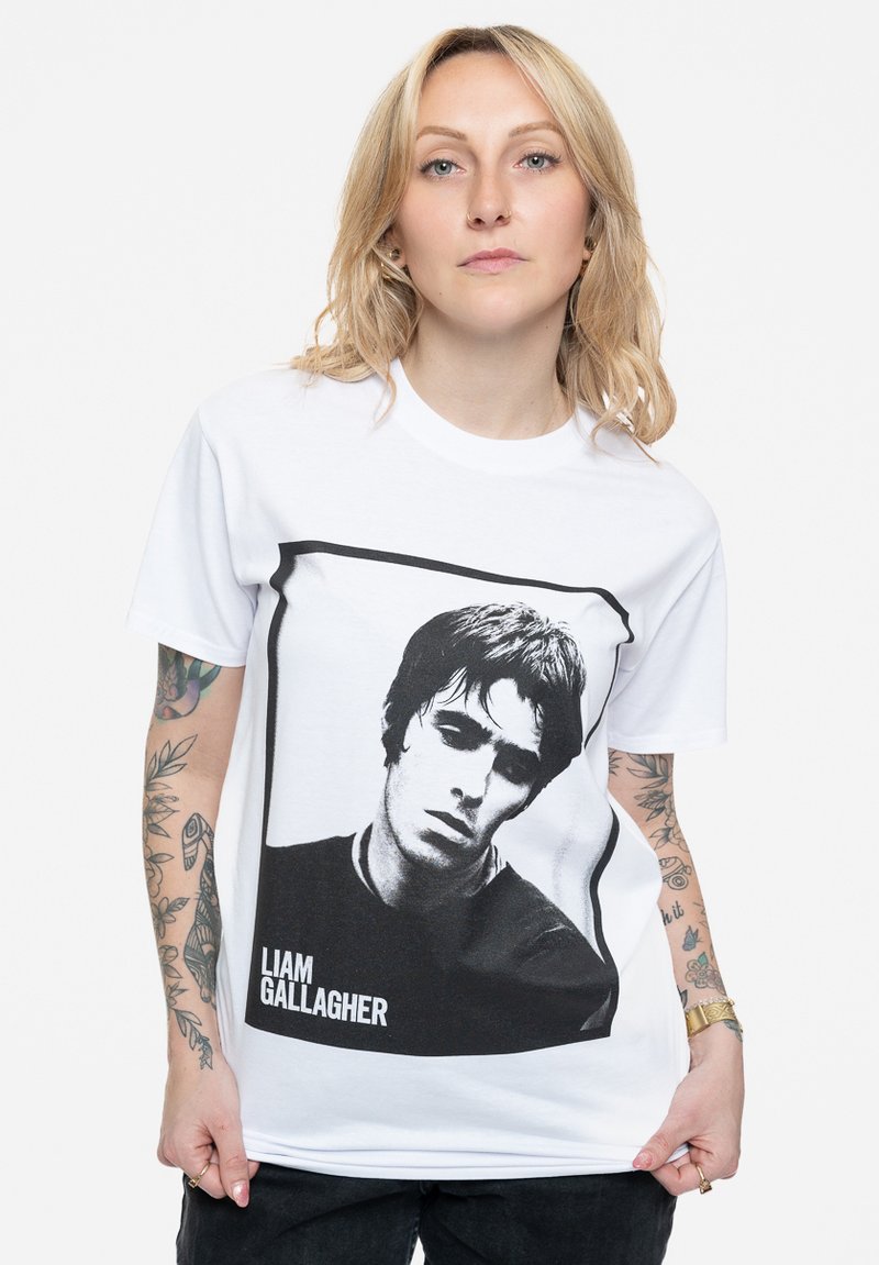 White cotton t-shirt featuring a black and white graphic of a man’s face, with the text "LIAM GALLAGHER" beneath the image. Short sleeves.