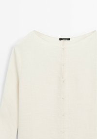 Weißes, strukturiertes Blusenshirt mit rundem Ausschnitt, langen Ärmeln und einer durchgehenden Knopfleiste mit hellen Knöpfen.