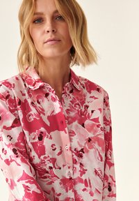 Blomstrede skjorte i pink nuancer med knappelukning, krave og lange ærmer. Letvægtsstof med et blandet blomsterdesign.