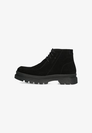 Schwarze Wildleder-Ankle-Boots mit strukturierter Oberfläche, kontrastierenden Znähten und einer robusten Gummisohle mit einem multidirektionalen Profil.