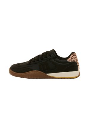 Zapatilla negra con cordones, suela marrón y detalle de estampado de leopardo en el talón, mostrada de perfil sobre fondo blanco.