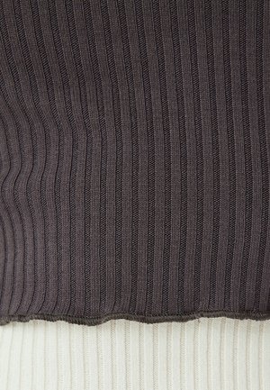 Maglione lavorato a maglia con texture a coste grigio scuro nella parte superiore, che sfuma in un tessuto a coste crema nella parte inferiore con orlo grezzo.