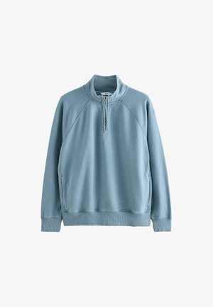 Jasnoniebieski polarowy pulower z wysokim kołnierzem, półzamkiem, rękawami raglanowymi oraz ściągaczami u mankietów i na dole. Gładka tekstura, casualowy design.