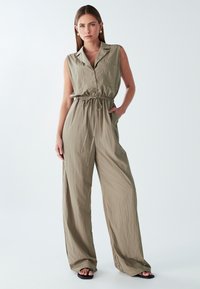 Combinaison sans manches vert olive avec une fermeture à boutons sur le devant, taille cintrée et pantalons à jambes larges en tissu léger et texturé.