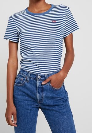 Niebieska i biała w paski koszulka z okrągłym dekoltem, krótkimi rękawami i małym czerwonym logo Levi's na piersi, zestawiona z niebieskimi dżinsami.