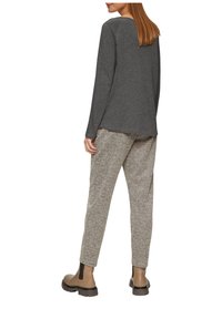 Grijze longsleeve top, losse pasvorm, gecombineerd met beige broek met houndstoothpatroon. Lichtbruin enkellaarsjes met elastische accenten aan de zijkant.