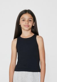 Zwarte geribbelde mouwloze tanktop met een ronde halslijn, aansluitend ontwerp en gladde textuur, gedragen met grijze shorts.