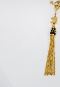 Goldene Kette mit Quaste und schwarzem, honigwabenmusterigem Deckel und Verschluss auf weißem Hintergrund.