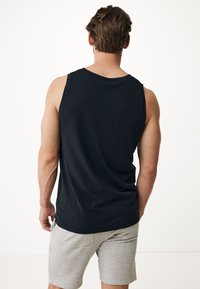 Svart bomullstopp med avslappnad passform, som visar baksidan och axeln. Parat med ljusgrå shorts med rak skärning och sidofickor.