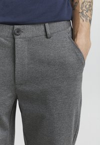 Gray tailored trousers made of textured fabric, featuring a button closure and side pockets, with a slim fit design.