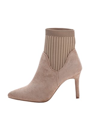 Stivale ankle in suede beige con punta affusolata, tomaia a maglia a coste simile a una calza e tacco alto sottile.