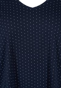 Granatowa tkanina z małymi, równomiernie rozmieszczonymi białymi groszkami i dekoltem w kształcie litery V.