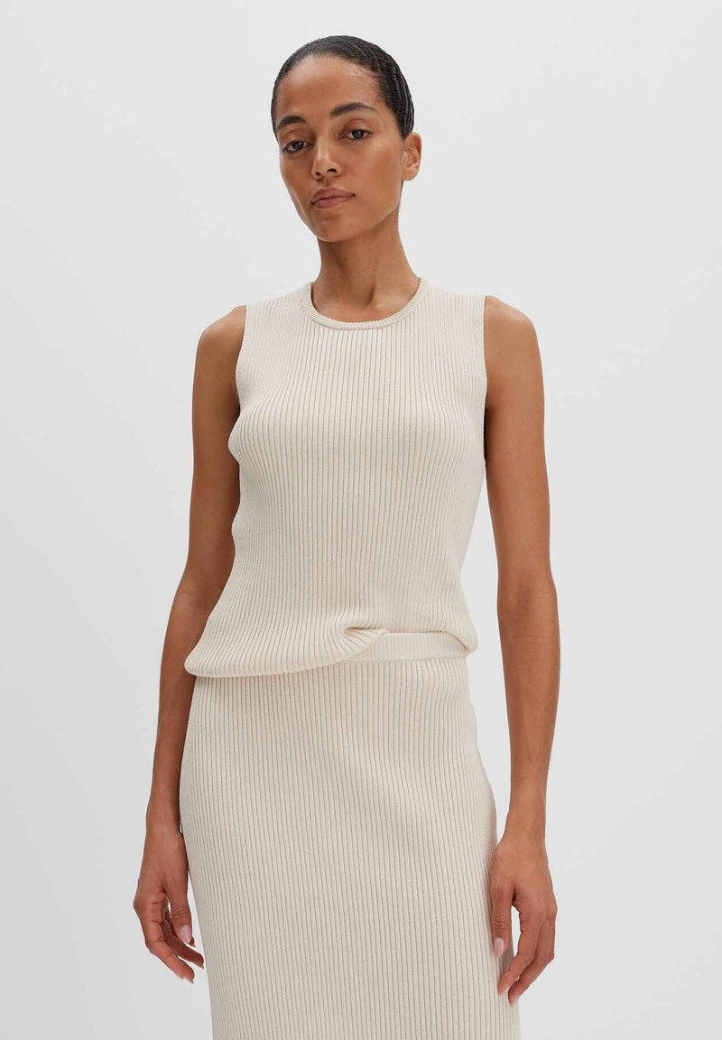 Top a coste color beige chiaro con scollatura rotonda e senza maniche. Tessuto morbido e silhouette aderente.