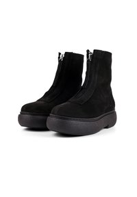 Schwarze Wildleder-Ankle-Boots mit hoher Sohle, ausgestattet mit einem Reißverschluss vorne und kontrastierenden Nähten entlang der Seiten.