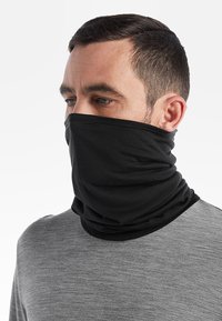 Svart halsduk gjord av mjukt, elastiskt tyg, som omsluter halsen och den nedre delen av ansiktet; bärs med en grå långärmad tröja.