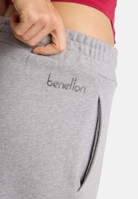 Szare dresowe spodnie z elastycznym pasem w talii, z boczną kieszenią i subtelnym logo nadrukowanym na tkaninie. Miękki, strukturalny materiał.