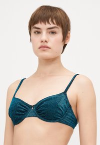 Tekorn glitrende bh med bøyle, samlet kopp og justerbare stropper. Har en liten nøkkelhullsdetalj i midten.