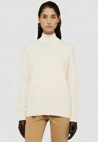 Cremfarbener Sweatshirt mit hohem Kragen aus glattem Stoff, mit überschnittenen Schultern und einem dezenten Logodetail am Saum.
