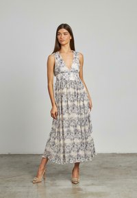 Maxikleid mit Blumenmuster in hellem Creme, mit tiefem V-Ausschnitt, ärmellosem Design und gerafftem Taillenbund, aus fließendem Stoff.