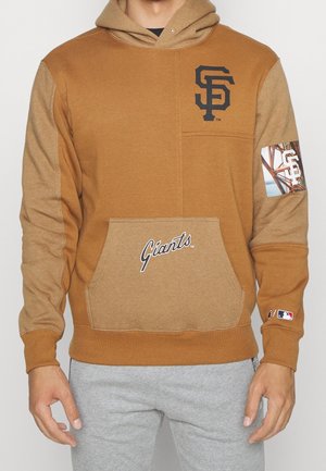 Brązowa bluza z kapturem z czarnym logo „SF”, wzorem na boku i napisem „Giants”. Miękka w dotyku, z przednią kieszenią i kapturem.