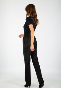 Pantalons noirs à coupe décontractée avec une taille élastique, associés à un t-shirt ajusté bleu marine, mettant en valeur des tissus lisses et des lignes épurées.