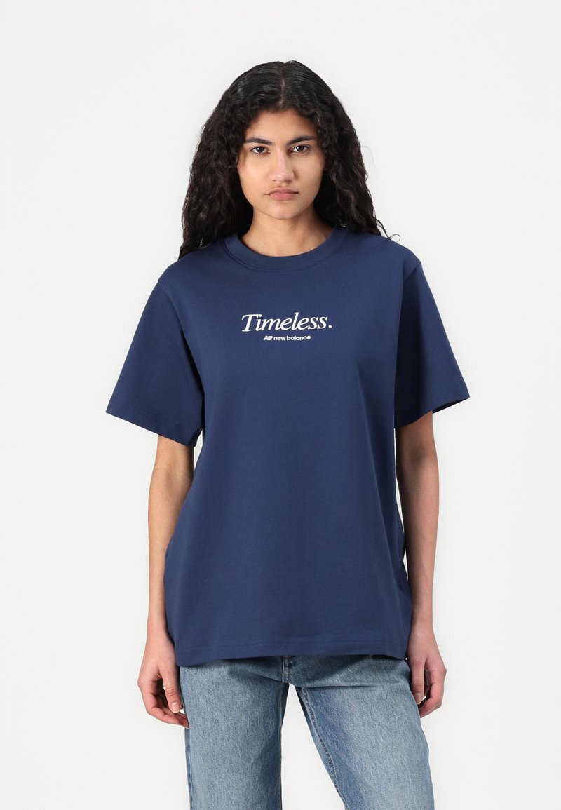 T-shirt en coton bleu marine à manches courtes, col rond, avec le texte blanc "Timeless" imprimé sur le devant. Coupe décontractée.