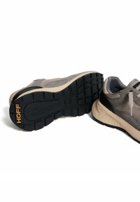 Zapatillas de ante gris con acentos en negro y crema, que cuentan con una suela de goma texturizada y la marca "HOFF" en el talón y la suela.