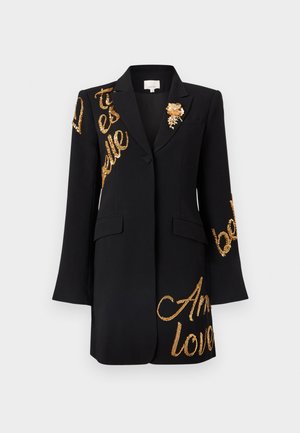 Black blazer with long sleeves, features gold sequined text and a floral brooch accent on the chest. Classic lapel and structured design.
