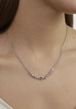 Silberne Halskette mit einem Unendlichkeitssymbol, verziert mit kleinen klaren Perlen entlang der Kette, mit einem zarten und glatten Design.