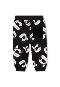 Pantaloni della tuta neri con volti di cartone animato ripetuti, capelli bianchi e occhiali da sole, cintura elastica e tasca posteriore in tessuto nero.