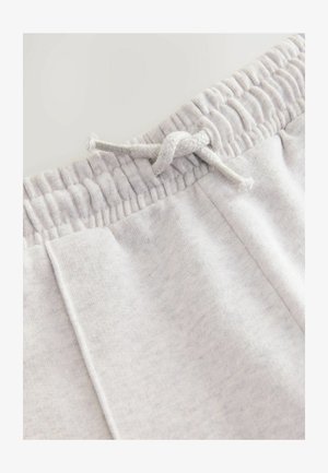 Pilkos medvilnės sportinės kelnės su elastingu juosmeniu ir sutraukiamąja virve, sklandžiu paviršiumi ir šoninėmis kišenėmis.