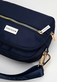Námořnická nylonová crossbody taška se zlatými doplňky, dvěma zipovými přihrádkami a texturovaným popruhem se značkou "Wittchen."