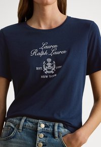 Tamnoplava pamučna majica s vezanim logotipom "Lauren Ralph Lauren" i grbom, okruglim izrezom i kratkim rukavima.