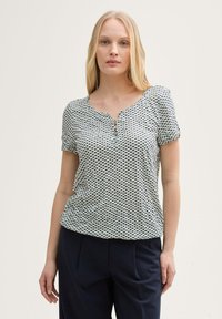 Haut léger à manches courtes avec un décolleté en V et des détails de boutons. Présente un motif à carreaux vert et noir sur fond blanc.
