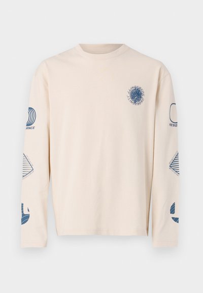 Long-sleeve, beige T-shirt made of cotton. Features blue graphic prints on the chest and sleeves, with various geometric designs.