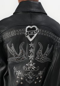 Veste en cuir noir avec des détails brodés : cœur avec "PINKO," hirondelles, étoiles et motifs floraux ornés de clous et d'accents en fil argenté.
