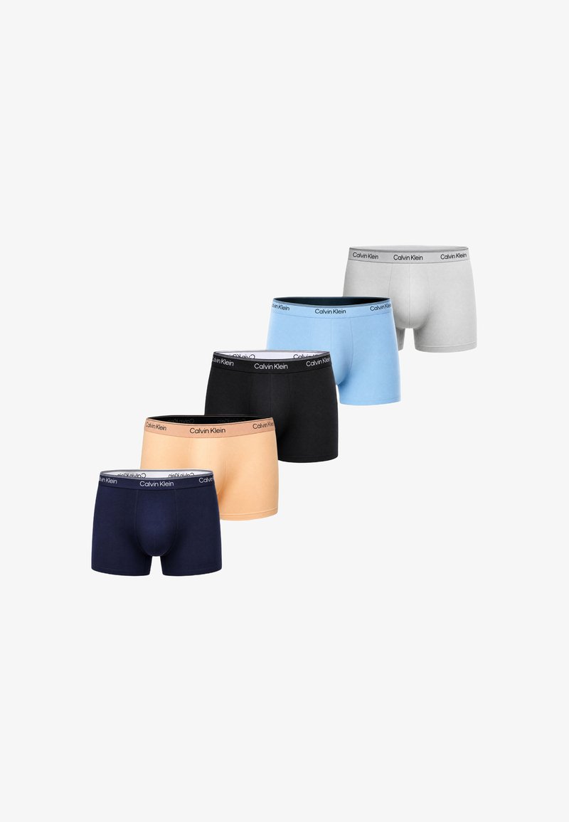 Cinq paires de caleçons pour hommes Calvin Klein en blanc, bleu clair, noir, beige et bleu marine disposées en diagonale.