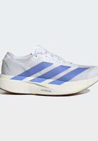 Scarpa da corsa bianca con tre strisce blu, suola beige spessa con etichetta Lightstrike Pro e lacci, vista di lato su sfondo neutro.