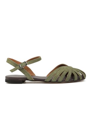 Płaska sandałka oliwkowa z wieloma zamszowymi paskami, klamrą przy kostce i odkrytym palcem na niskiej czarnej podeszwie.