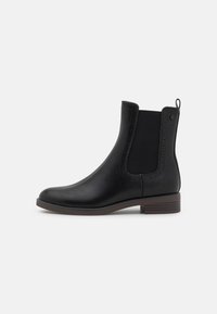 Botas de tobillo de cuero negro con lados elásticos, detalles ondulados y un bajo tacón cuadrado. Textura suave y diseño de punta redondeada.