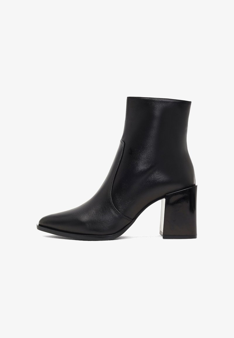 Bottine noire en cuir lisse, avec un nez pointu, un haut talon bloc et un design minimaliste sans quincaillerie visible.