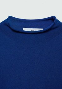 Modra pletena jopica s okroglim izrezom. Gladka tekstura, rebrasti detajli na robovih in oznaka z logotipom vidna zadaj.