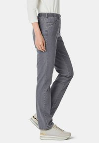 Graue Jeans mit elastischem Bund, seitlichen Taschen, schlanker Passform und einer dezenten Textur. Kombiniert mit hellgrauen Sneakers mit metallischen Akzenten.