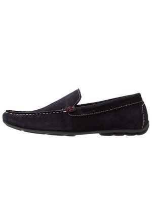 Mocassino da uomo in camoscio nero con cuciture bianche, dettaglio rosso e suola in gomma, mostrato di profilo su sfondo bianco.