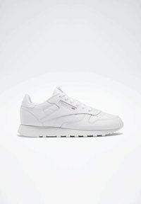 Fehér sneaker szintetikus anyagból, sima felülettel. Fűzős kialakítással, perforációkkal az orrán és gumitalppal rendelkezik.
