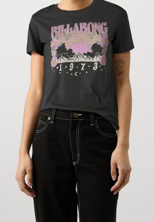 Black T-shirt featuring a graphic print with "BILLABONG" text, sun, mountains, flowers, and stars in muted colors; round neckline, short sleeves.