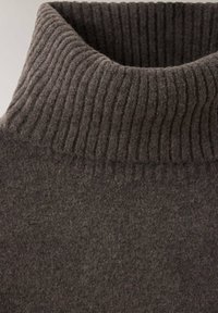 Col roulé en maille côtelée gris foncé sur un pull en laine douce, vu en gros plan.